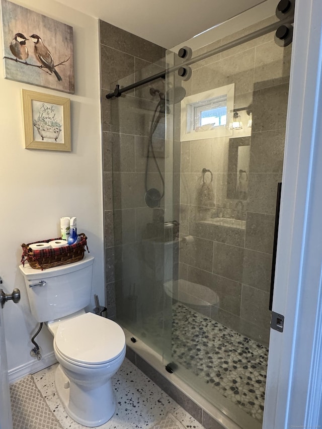 bathroom featuring toilet, tile patterned floors, and a shower with shower door