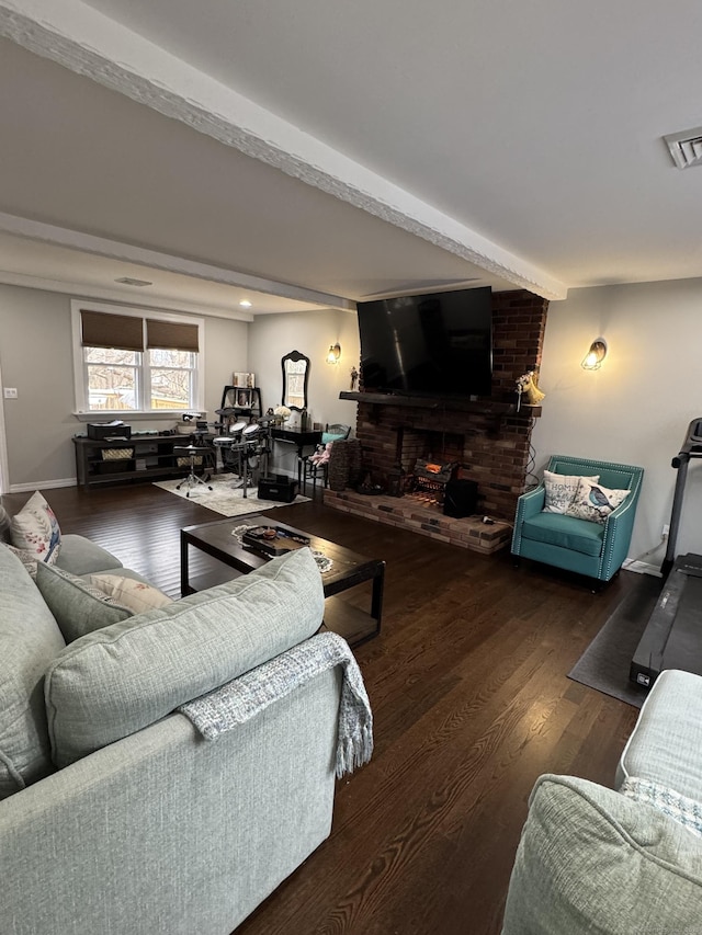 living room featuring dark wood-type flooring, a brick fireplace, and beam ceiling