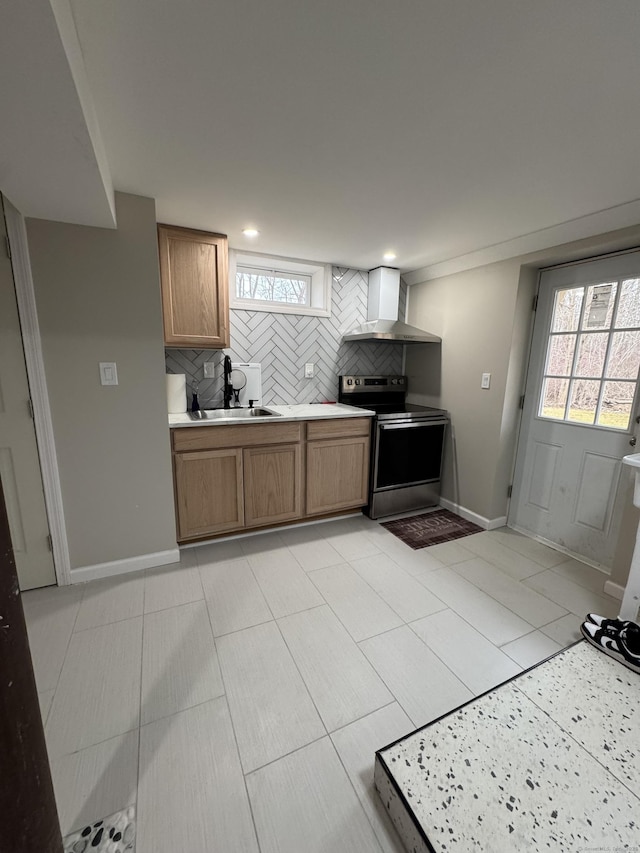 kitchen featuring a wealth of natural light, wall chimney range hood, sink, backsplash, and stainless steel electric range oven