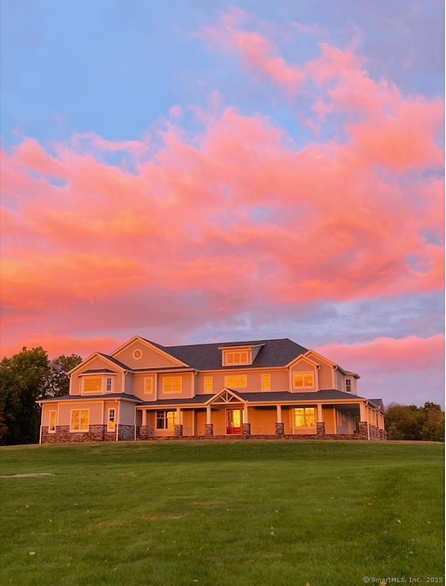 rear view of property featuring a lawn and stone siding