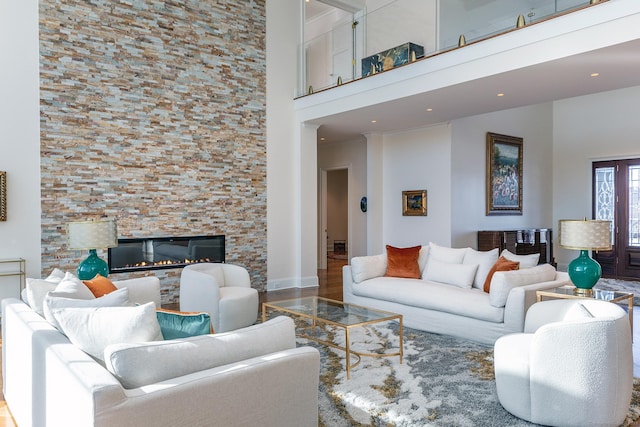 living room with wood finished floors, recessed lighting, a glass covered fireplace, and a high ceiling