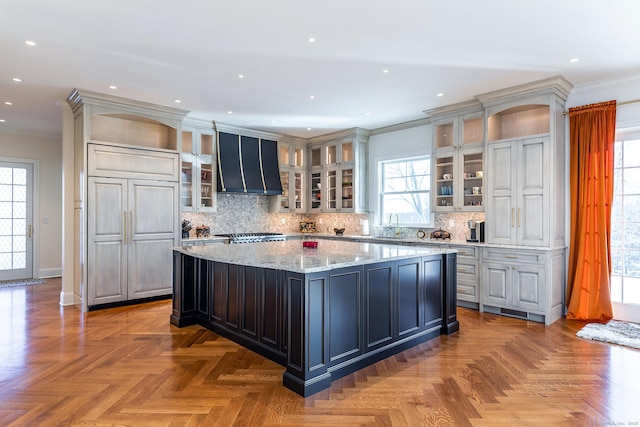 kitchen featuring ornamental molding, a center island, built in fridge, tasteful backsplash, and exhaust hood