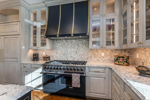 kitchen featuring backsplash, light stone countertops, double oven range, and wall chimney exhaust hood