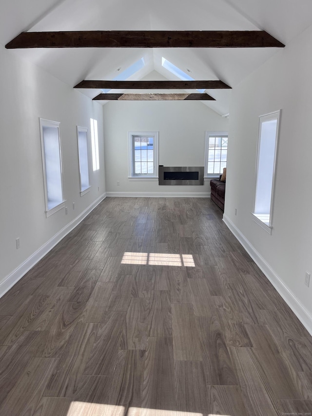 unfurnished living room with a healthy amount of sunlight, baseboards, lofted ceiling with beams, and dark wood-style floors