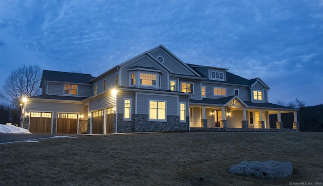 craftsman inspired home with a garage, a front yard, a porch, and stone siding