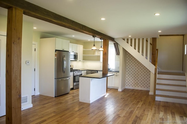 kitchen featuring dark countertops, appliances with stainless steel finishes, open shelves, wood finished floors, and white cabinetry