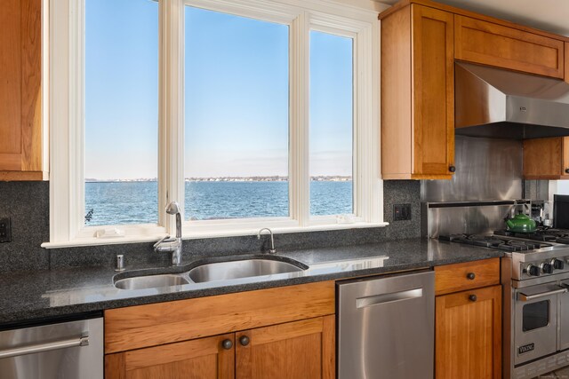 kitchen featuring a wealth of natural light, appliances with stainless steel finishes, wall chimney exhaust hood, and a water view