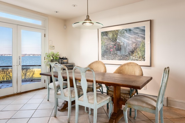 tiled dining space featuring a water view and french doors