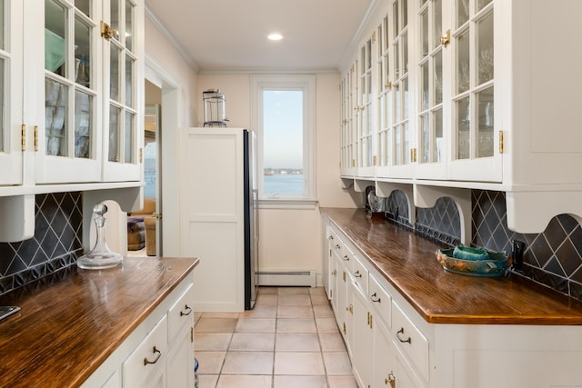 kitchen featuring white cabinets, a baseboard heating unit, backsplash, ornamental molding, and light tile patterned flooring