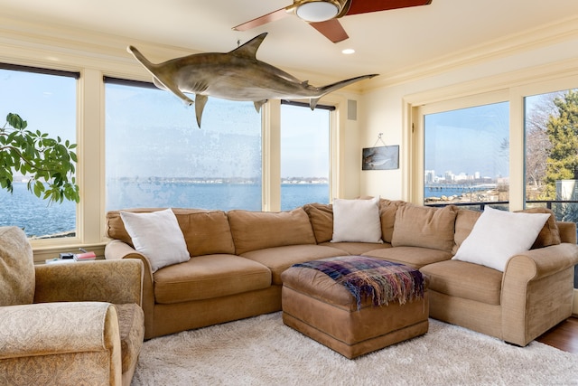 living room with ceiling fan, a wealth of natural light, a water view, and ornamental molding