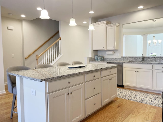 kitchen with stainless steel dishwasher, sink, a breakfast bar area, and white cabinets