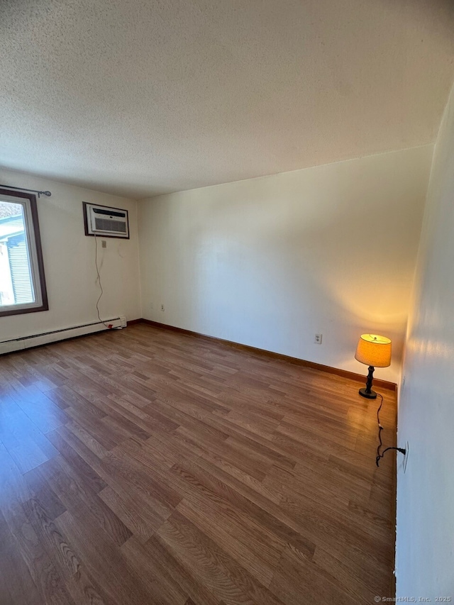 unfurnished room featuring a baseboard radiator, dark wood-type flooring, a textured ceiling, and a wall mounted air conditioner