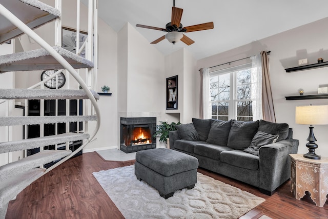 living room featuring vaulted ceiling, ceiling fan, dark hardwood / wood-style floors, and a tile fireplace