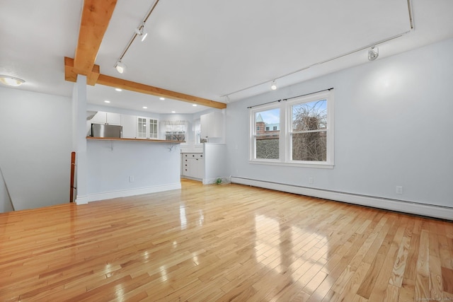 unfurnished living room with a baseboard heating unit, rail lighting, light hardwood / wood-style floors, and beamed ceiling