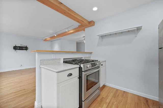 kitchen featuring kitchen peninsula, stainless steel range with gas stovetop, white cabinetry, light wood-type flooring, and rail lighting