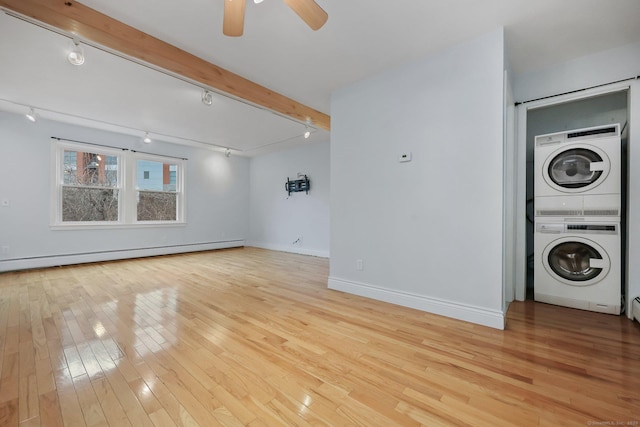 laundry area with track lighting, a baseboard radiator, light hardwood / wood-style flooring, and stacked washing maching and dryer