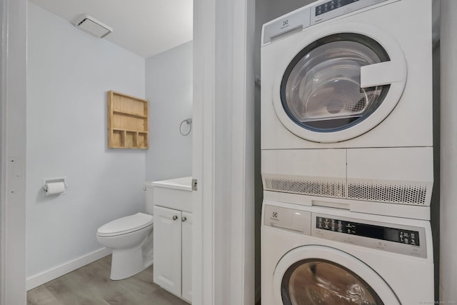 washroom with light wood-type flooring and stacked washer and clothes dryer