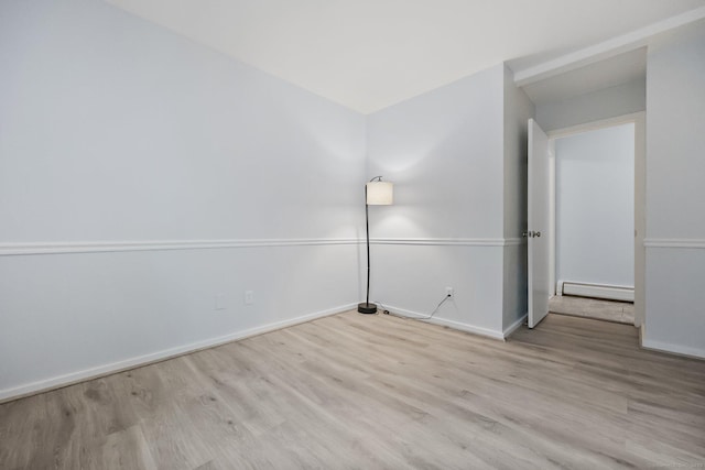 spare room with a baseboard heating unit and light hardwood / wood-style flooring