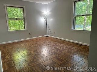 spare room with dark parquet flooring and a healthy amount of sunlight