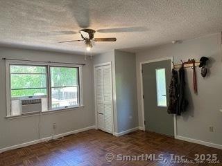 unfurnished bedroom with a closet, ceiling fan, cooling unit, and dark parquet flooring