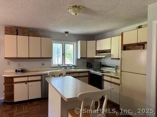 kitchen featuring a textured ceiling, white fridge, a kitchen island, dark parquet floors, and range with electric stovetop