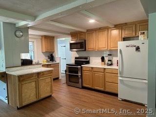 kitchen with wood-type flooring, beamed ceiling, and appliances with stainless steel finishes