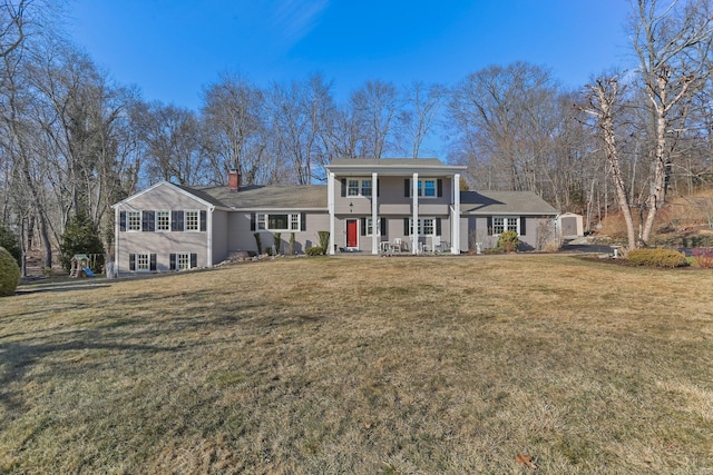 greek revival house with covered porch, a chimney, and a front lawn