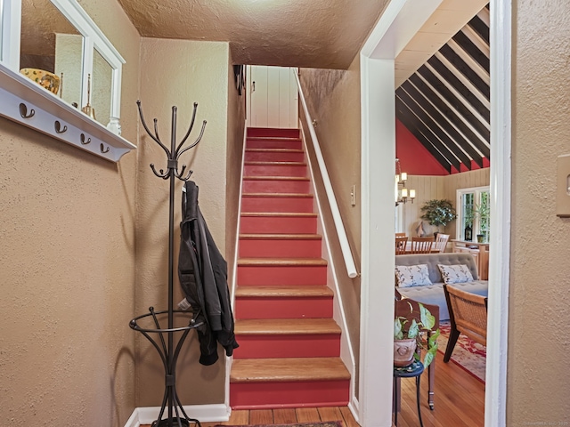 stairway with vaulted ceiling, a chandelier, and hardwood / wood-style floors