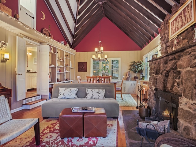 living room with hardwood / wood-style floors, high vaulted ceiling, wooden walls, a fireplace, and an inviting chandelier