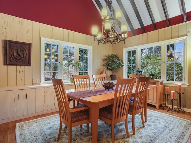 dining room featuring lofted ceiling with beams, light wood-type flooring, and a notable chandelier