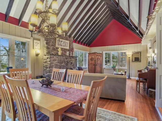 dining room with wood-type flooring, high vaulted ceiling, a chandelier, and beam ceiling