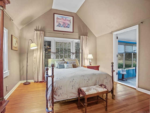 bedroom with vaulted ceiling, access to outside, and light hardwood / wood-style flooring