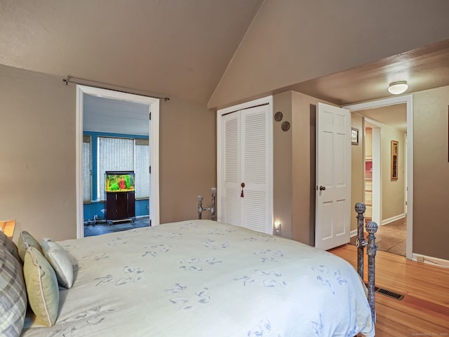 bedroom featuring wood-type flooring, lofted ceiling, and a closet