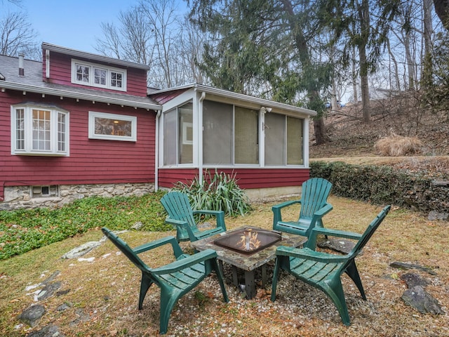 back of house featuring a sunroom and an outdoor fire pit