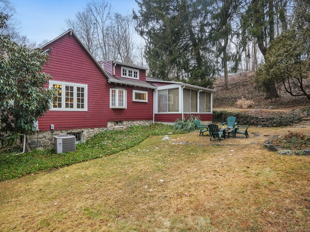 back of property featuring a sunroom, central air condition unit, and a lawn