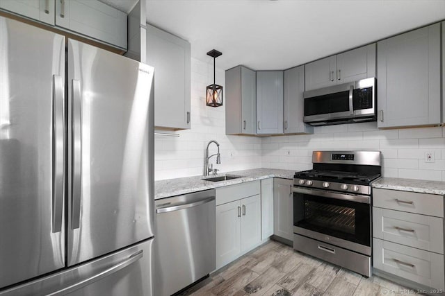 kitchen featuring sink, light stone counters, stainless steel appliances, and light hardwood / wood-style floors