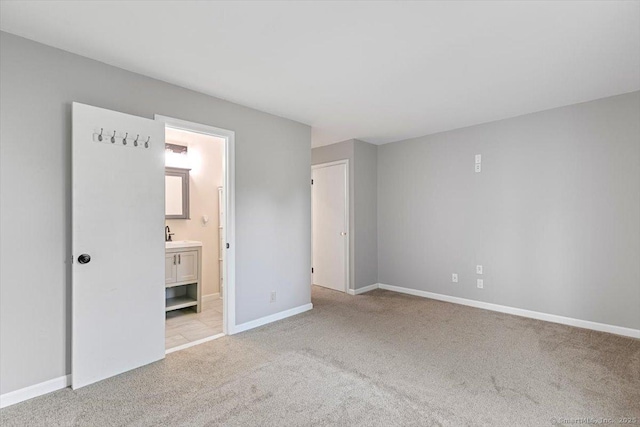 unfurnished bedroom featuring ensuite bathroom and light colored carpet