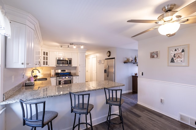 kitchen featuring white cabinetry, kitchen peninsula, stainless steel appliances, a breakfast bar, and sink