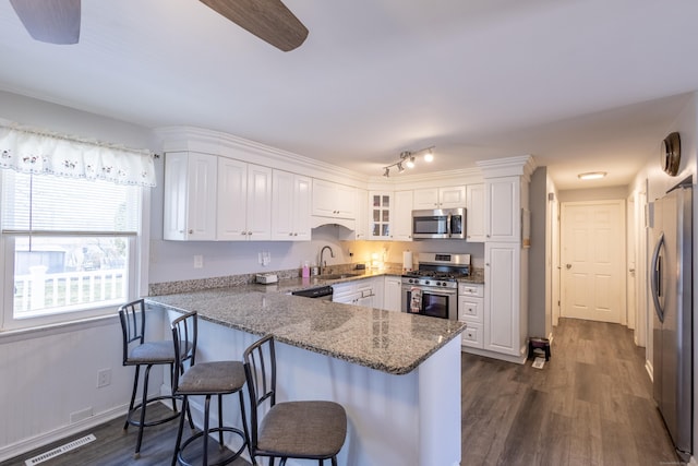 kitchen with kitchen peninsula, appliances with stainless steel finishes, sink, and white cabinetry