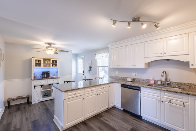 kitchen with kitchen peninsula, dishwasher, sink, and white cabinetry