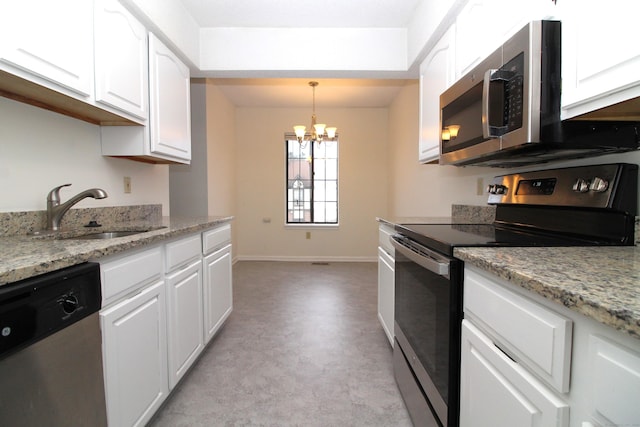 kitchen featuring white cabinets, decorative light fixtures, stainless steel appliances, sink, and light stone counters