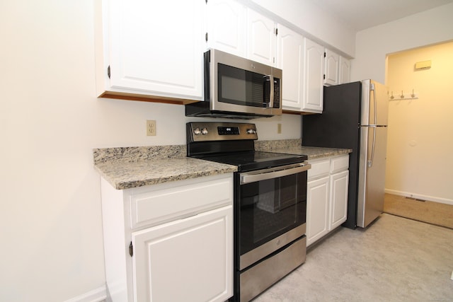 kitchen featuring appliances with stainless steel finishes, white cabinetry, and light stone counters