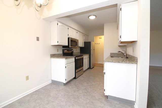 kitchen featuring light stone countertops, white cabinets, appliances with stainless steel finishes, and sink