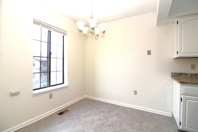 unfurnished dining area with light colored carpet and a notable chandelier