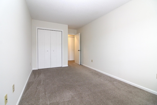 unfurnished bedroom with a closet and dark colored carpet