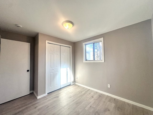 unfurnished bedroom with light wood-type flooring and a closet