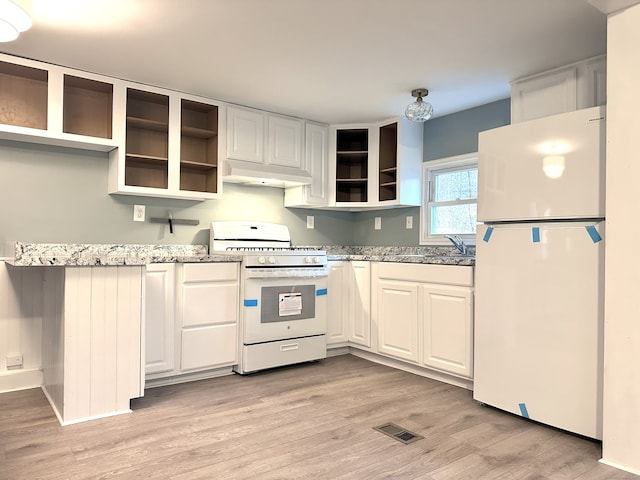 kitchen with sink, white cabinets, light stone counters, and white appliances