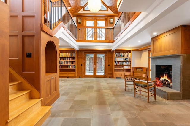 interior space featuring french doors, a towering ceiling, and built in shelves