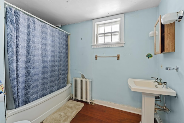 bathroom with hardwood / wood-style flooring, radiator, and shower / tub combo with curtain