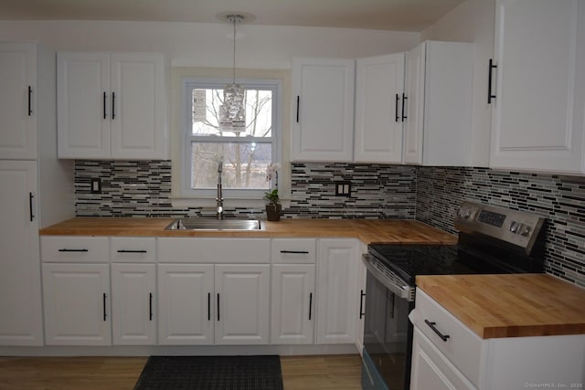 kitchen with butcher block counters, electric range, and white cabinetry